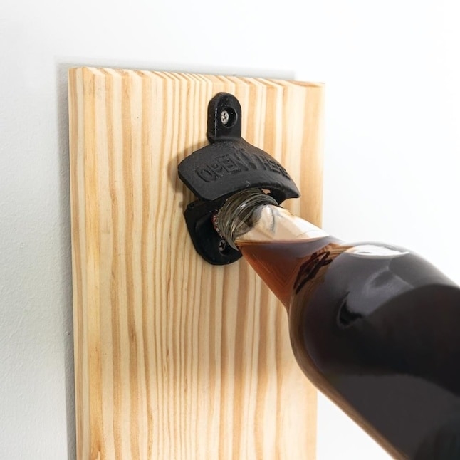 the bottle opener mounted to a wall opening a bottle