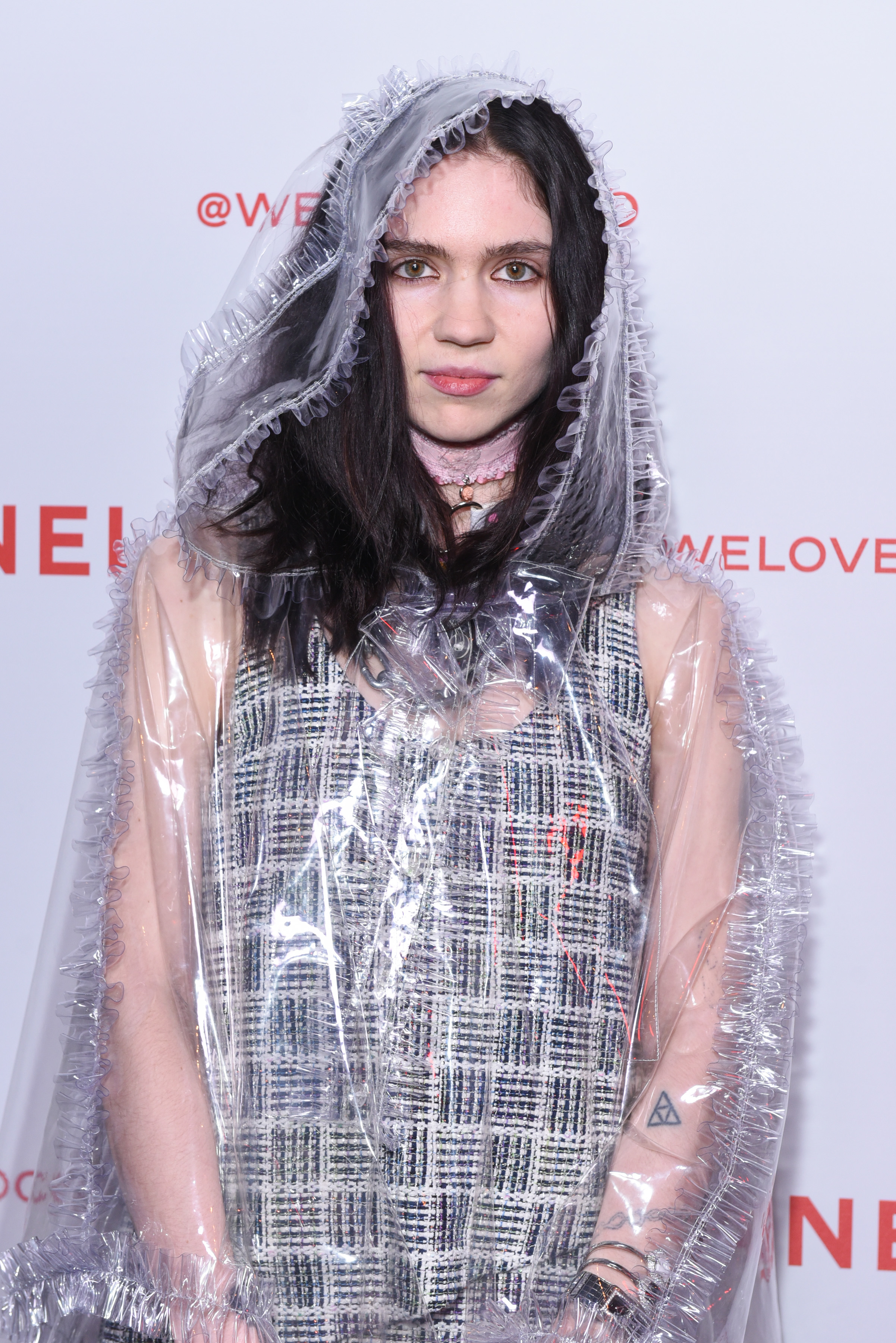 Grimes on the red carpet in a metallic dress and a transparesnt poncho/hooded coat