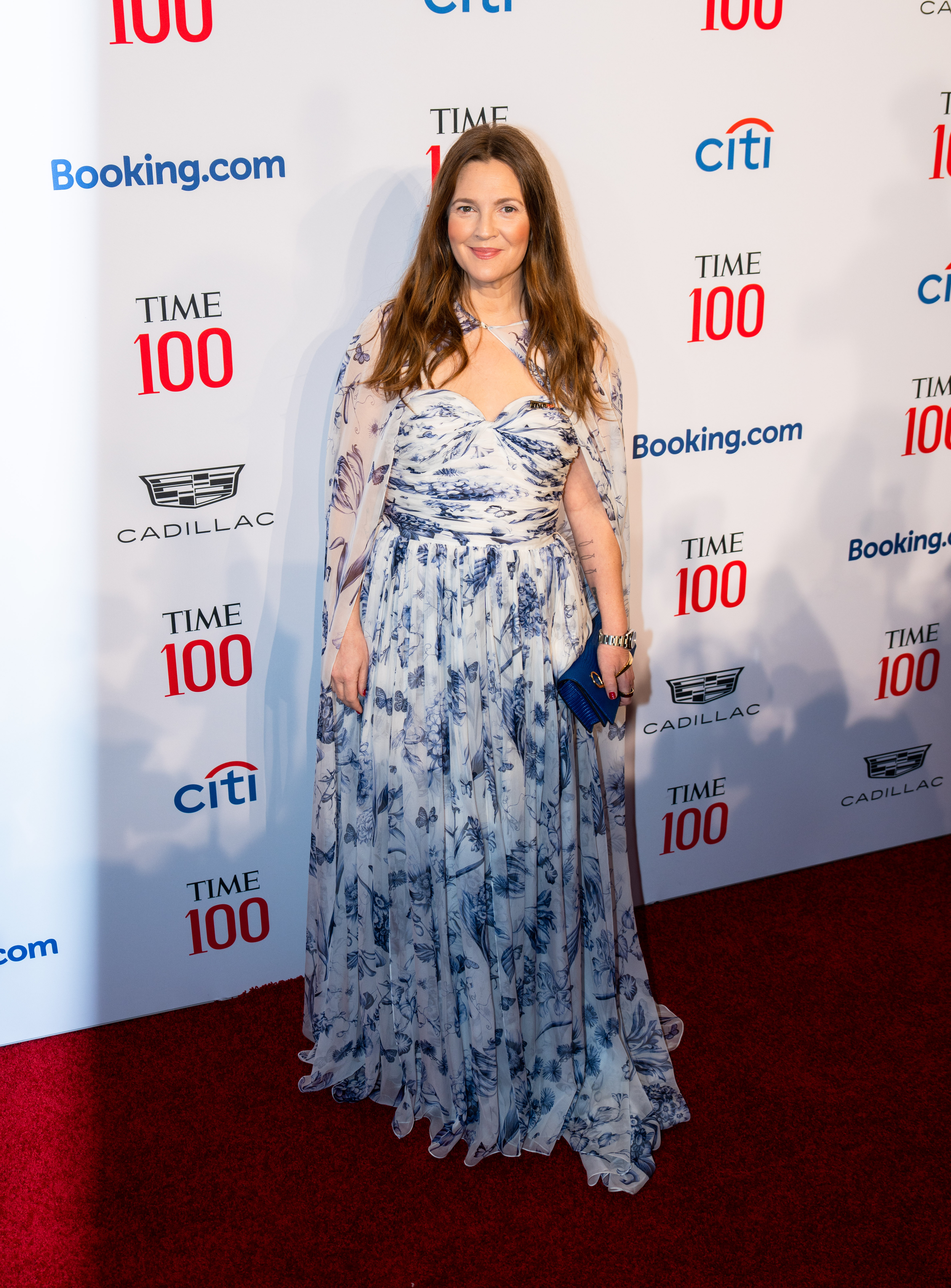 Drew Barrymore stands on the red carpet in a flow-y strapless dress with a matching cape