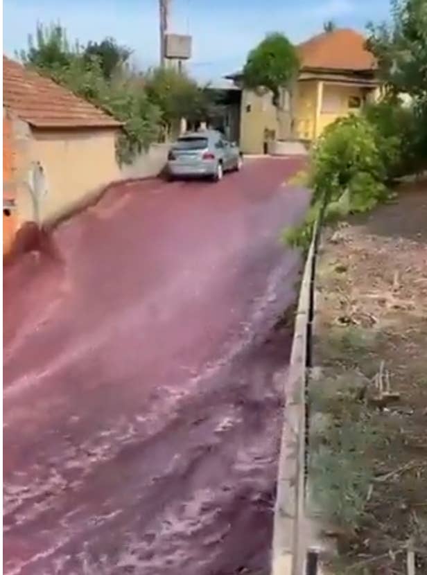Top of hill where red wine river is flowing, car pictured parked in the river