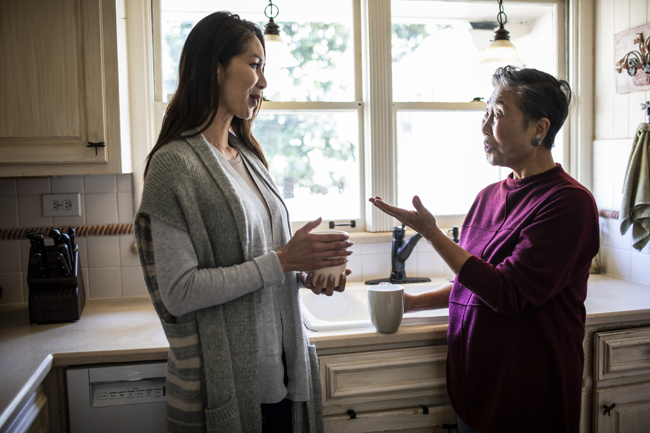 An older woman is speaking with a younger woman in a kitchen