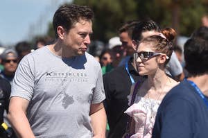 Elon Musk and Grimes look at each other while walking on the street