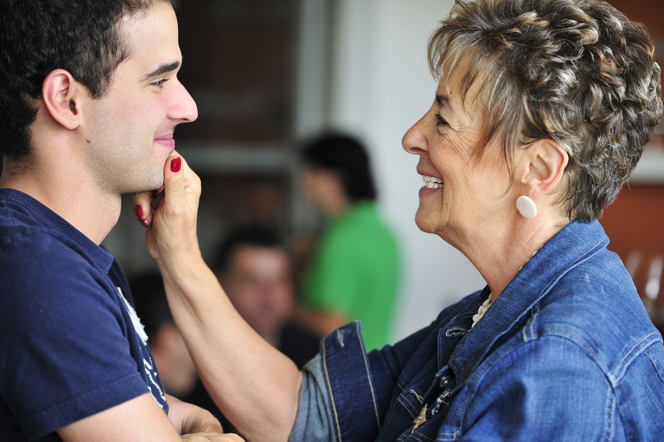 A grandma is pinching her adult grandson&#x27;s chin