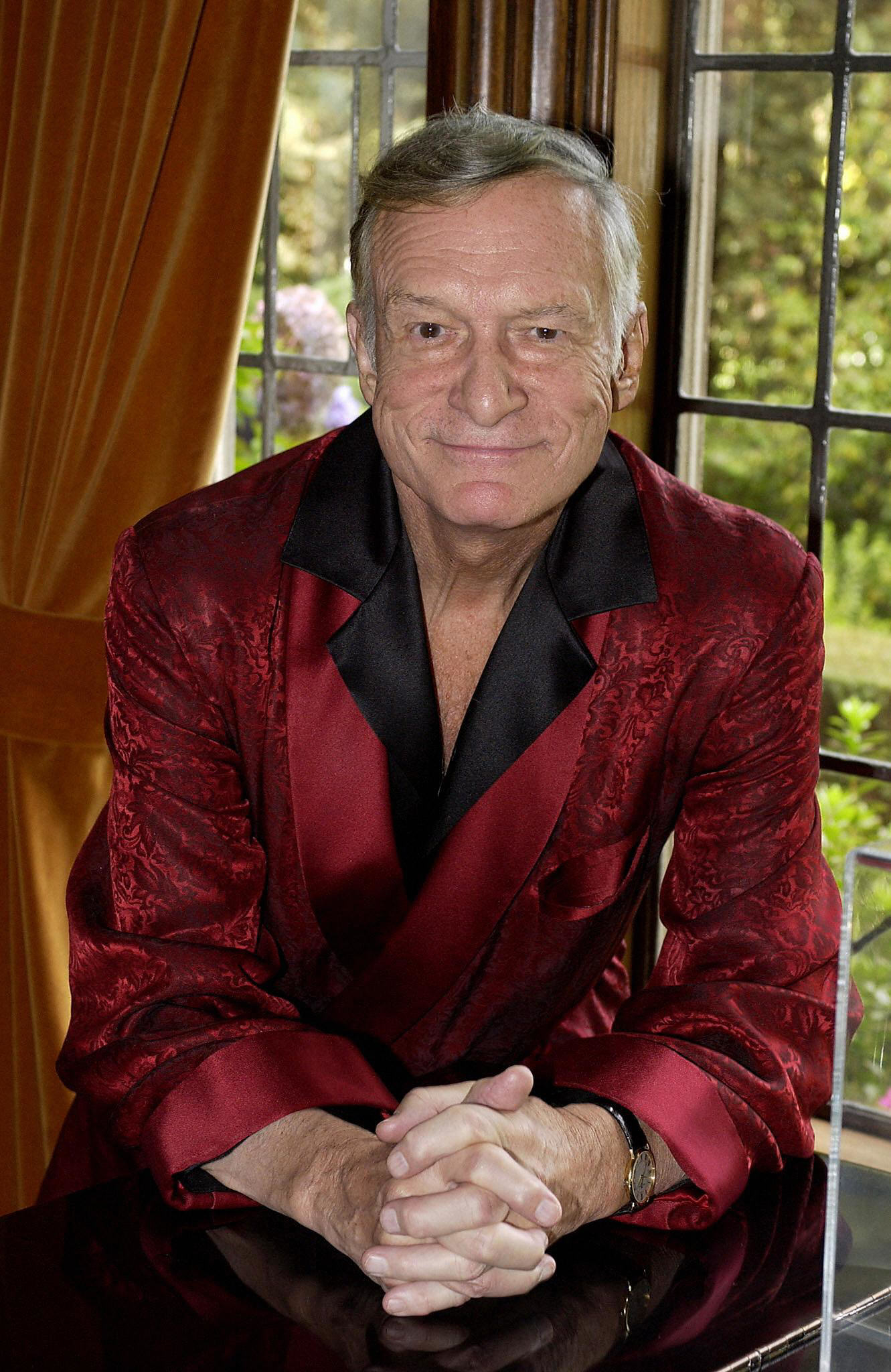 Hugh Hefner smiling for a photo while wearing his robe