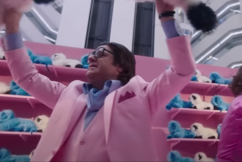 A man in a pink suit with a bunch of Beanie Babies in the background