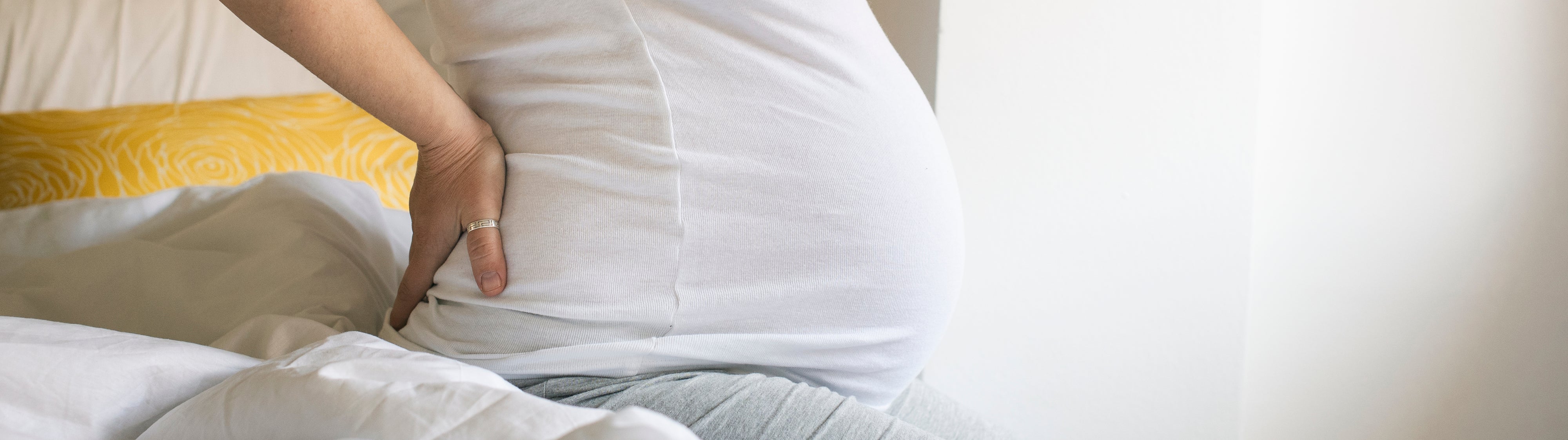 A pregnant woman stretching in bed