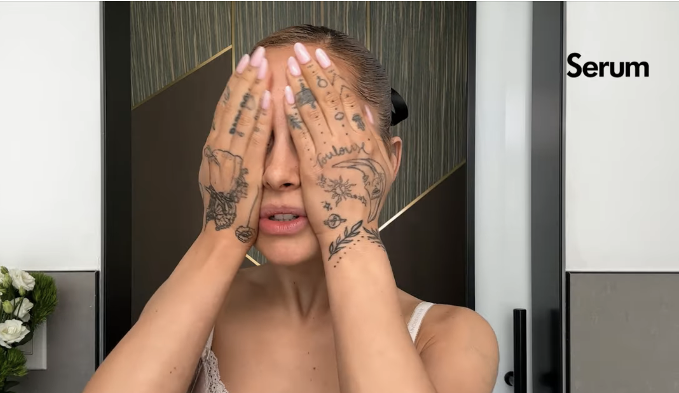 ariana covering her face as she applies serum to her face