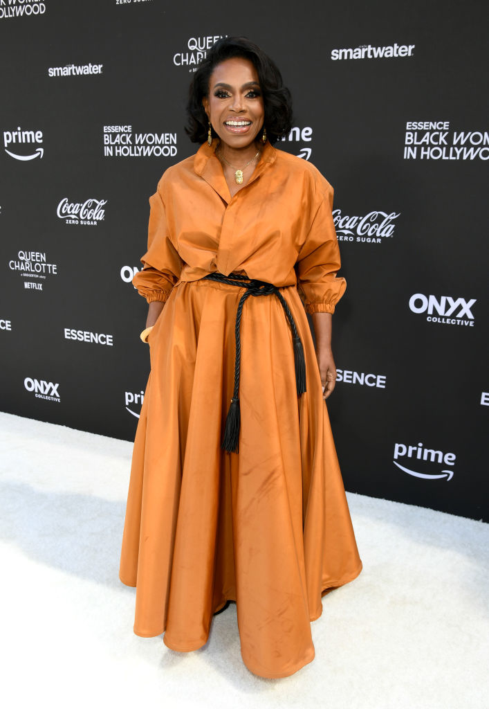 Sheryl Lee Ralph poses on the red carpet in a long, trenchcoat-esque gown with a full skirt and rope belt
