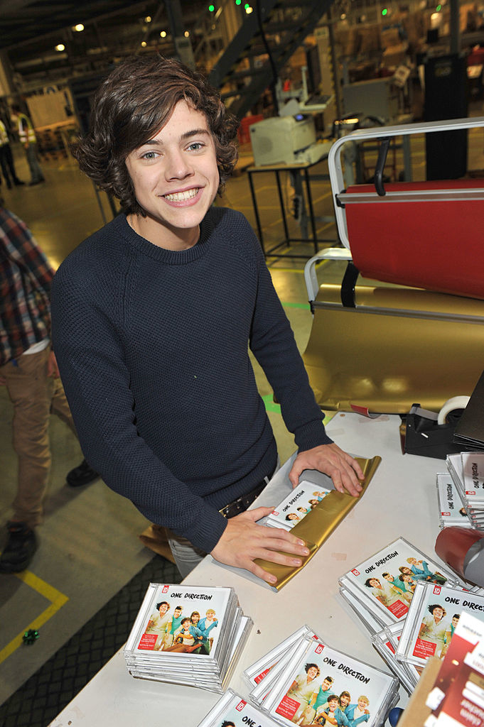 closeup of harry signing and wrapping one direction cds