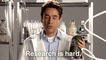 Fred Armisen dressed as a doctor in a white lab coat says "Research is hard."