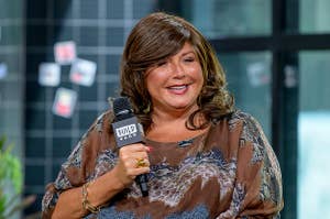 Abby Lee Miller smiles while holding a microphone