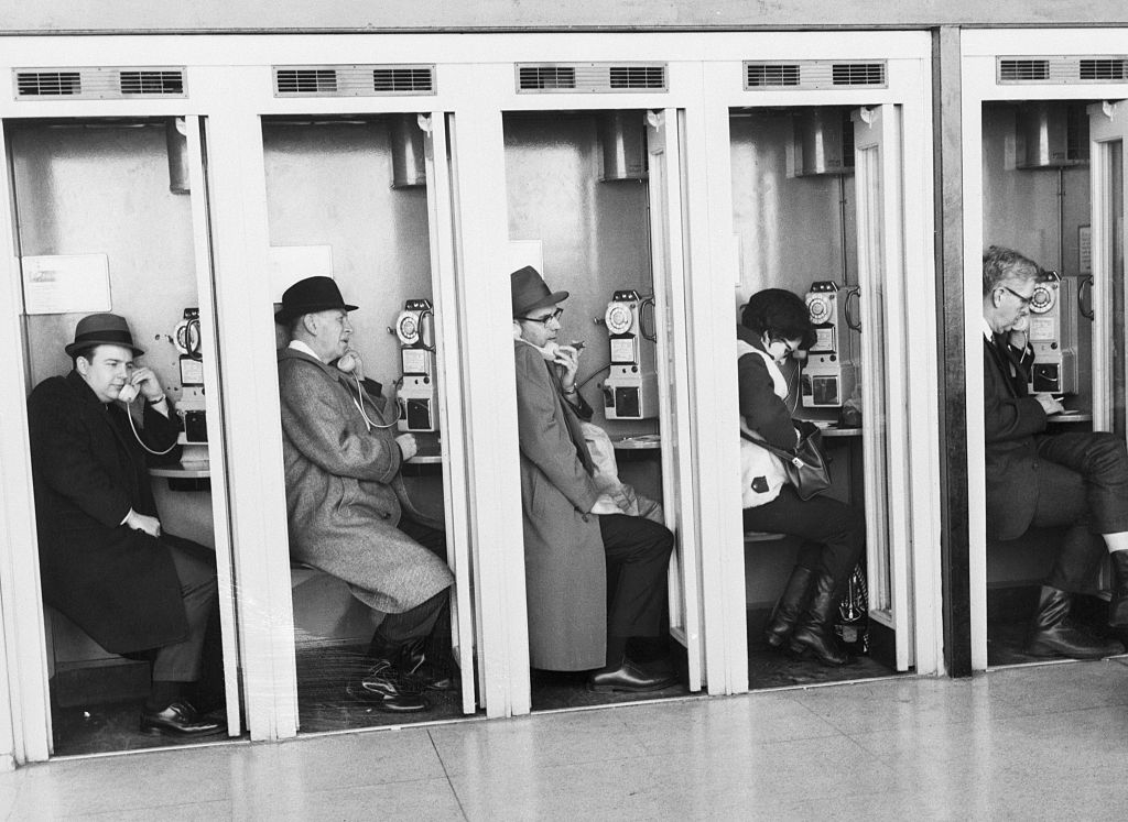row of people sitting in the phone booths