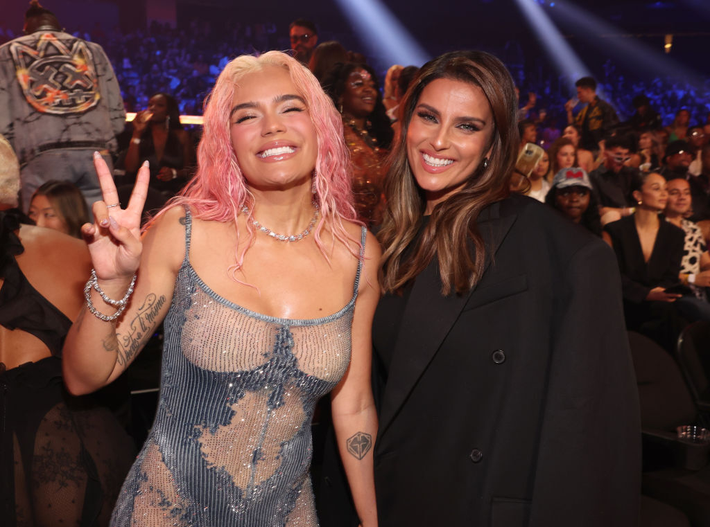 Karol G flashes the peace sign as she poses next to Nelly Furtado