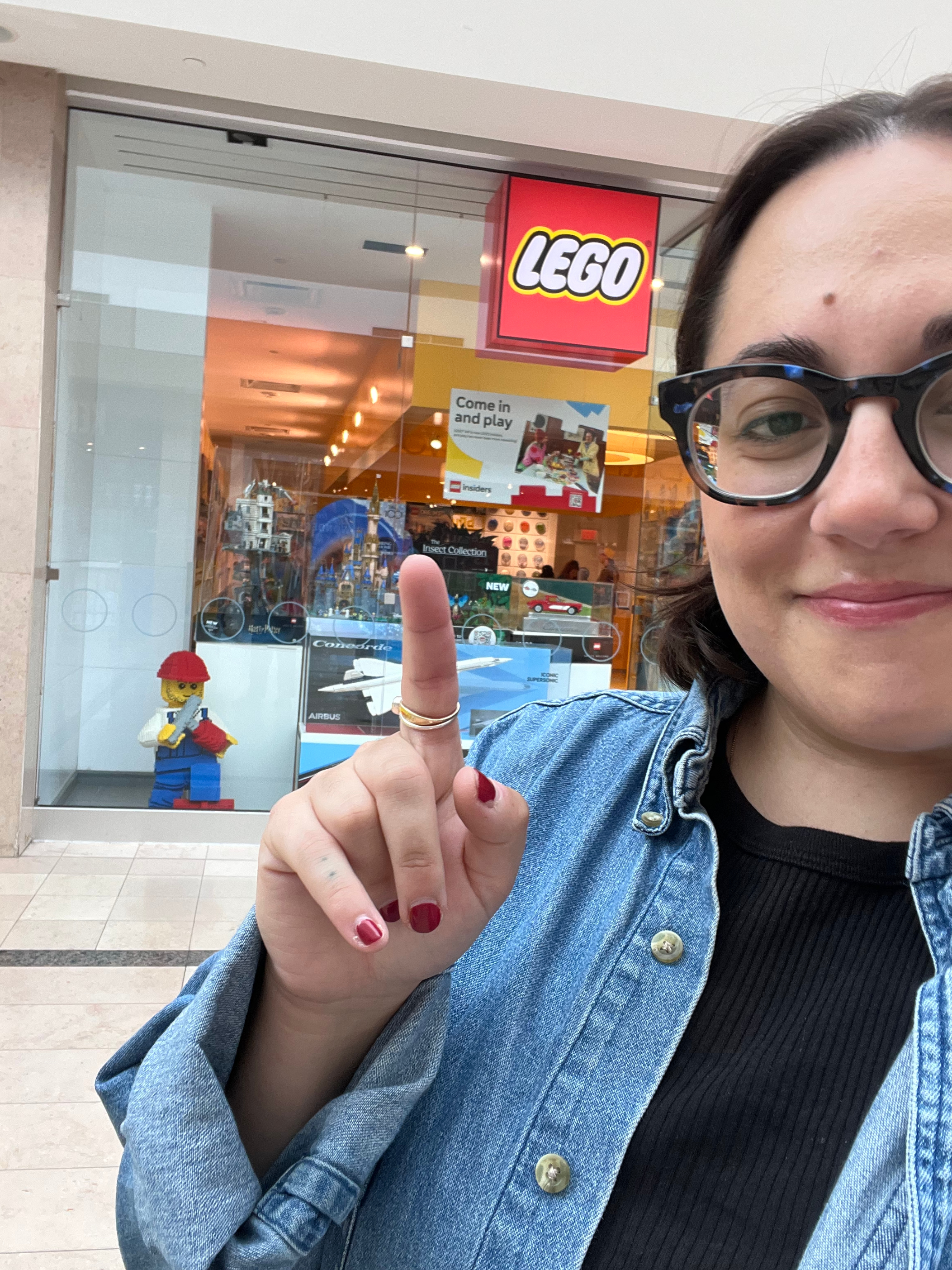 author pointing to LEGO store sign