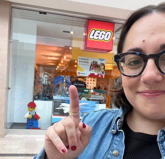 author pointing to LEGO store sign