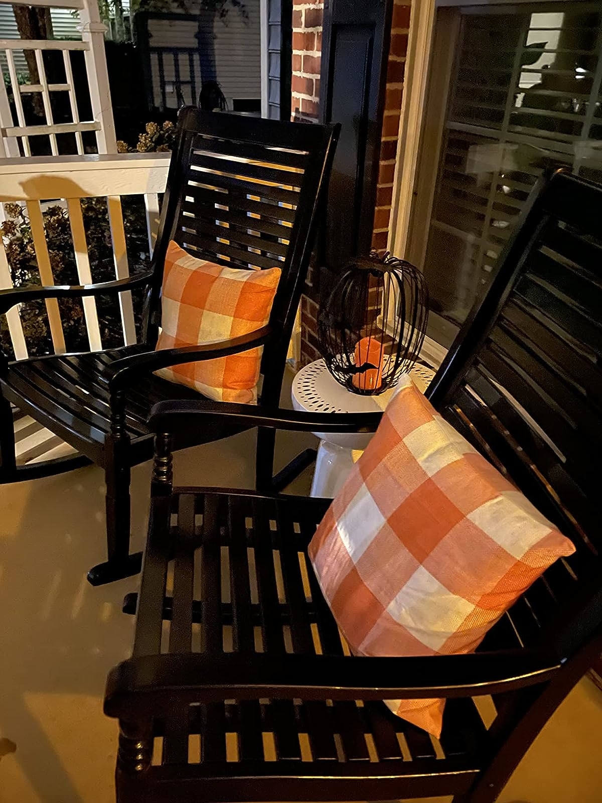 Reviewer image of the orange and white throw pillows on black outdoor chairs