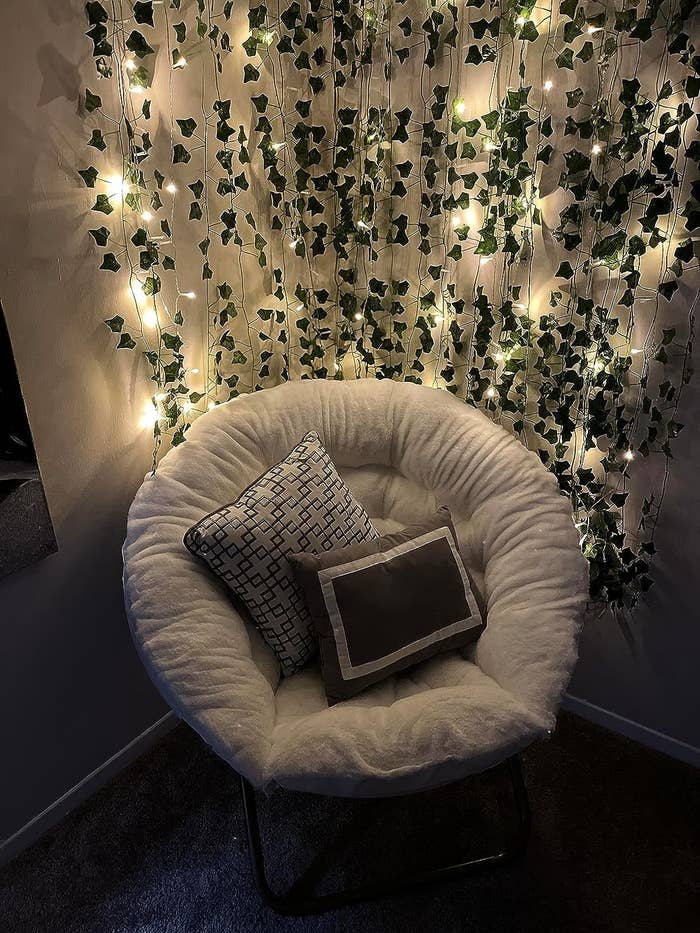 Reviewer image of the gray chair with pillows on it and lit up garland behind it