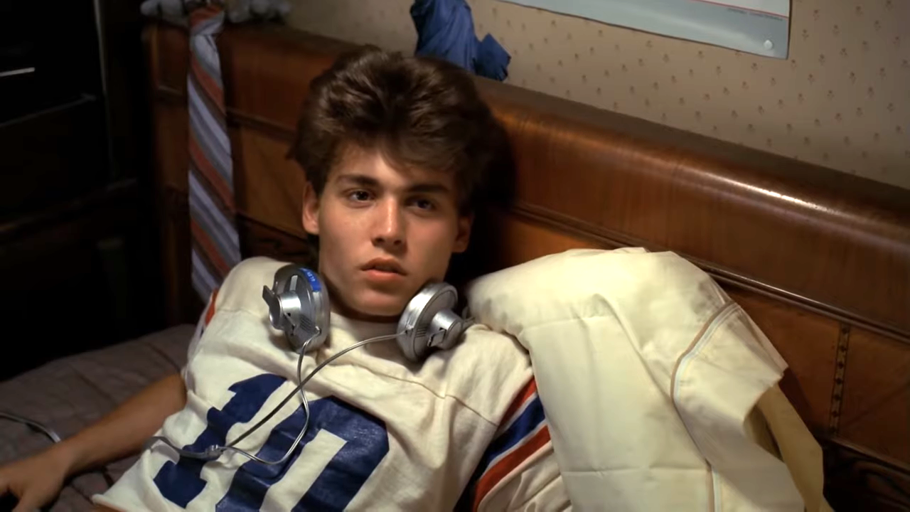 young johnny with headphones in bed