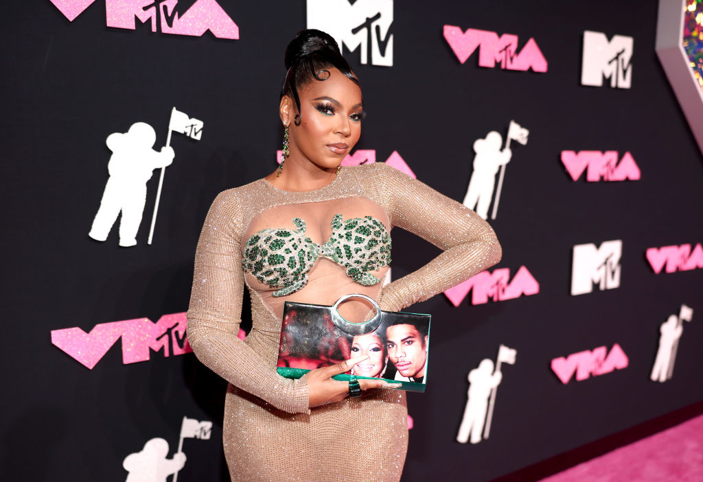 closeup of her holding a purse that has a photo of her and nelly together