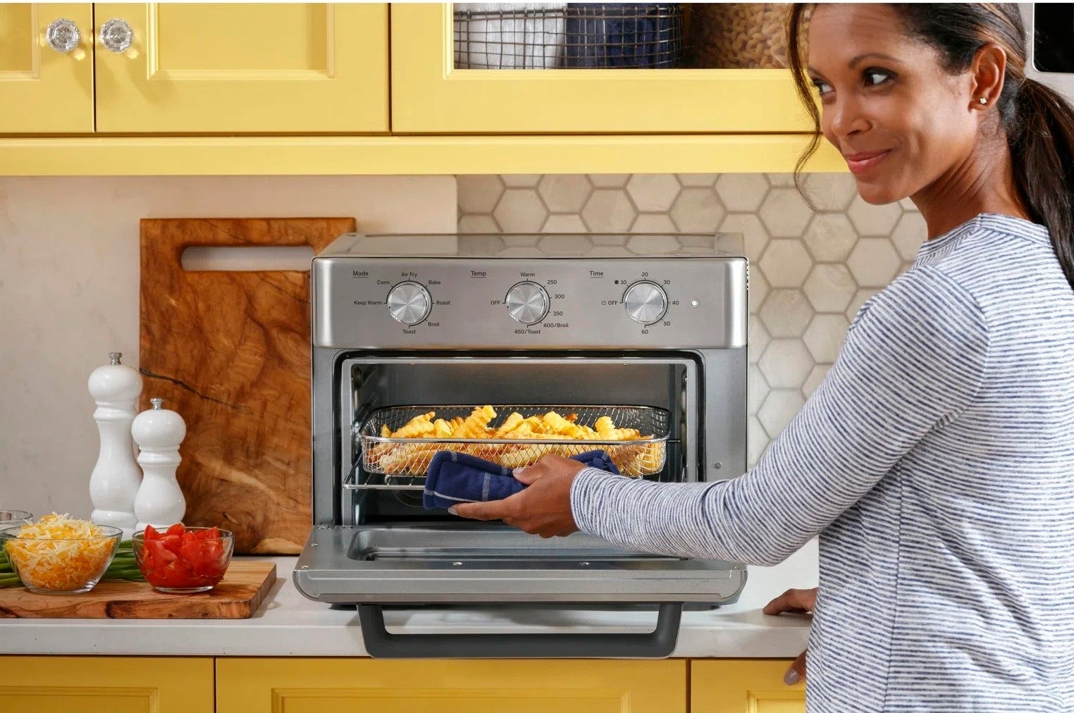 A model removing french fries from the toast oven, which has a wired basket