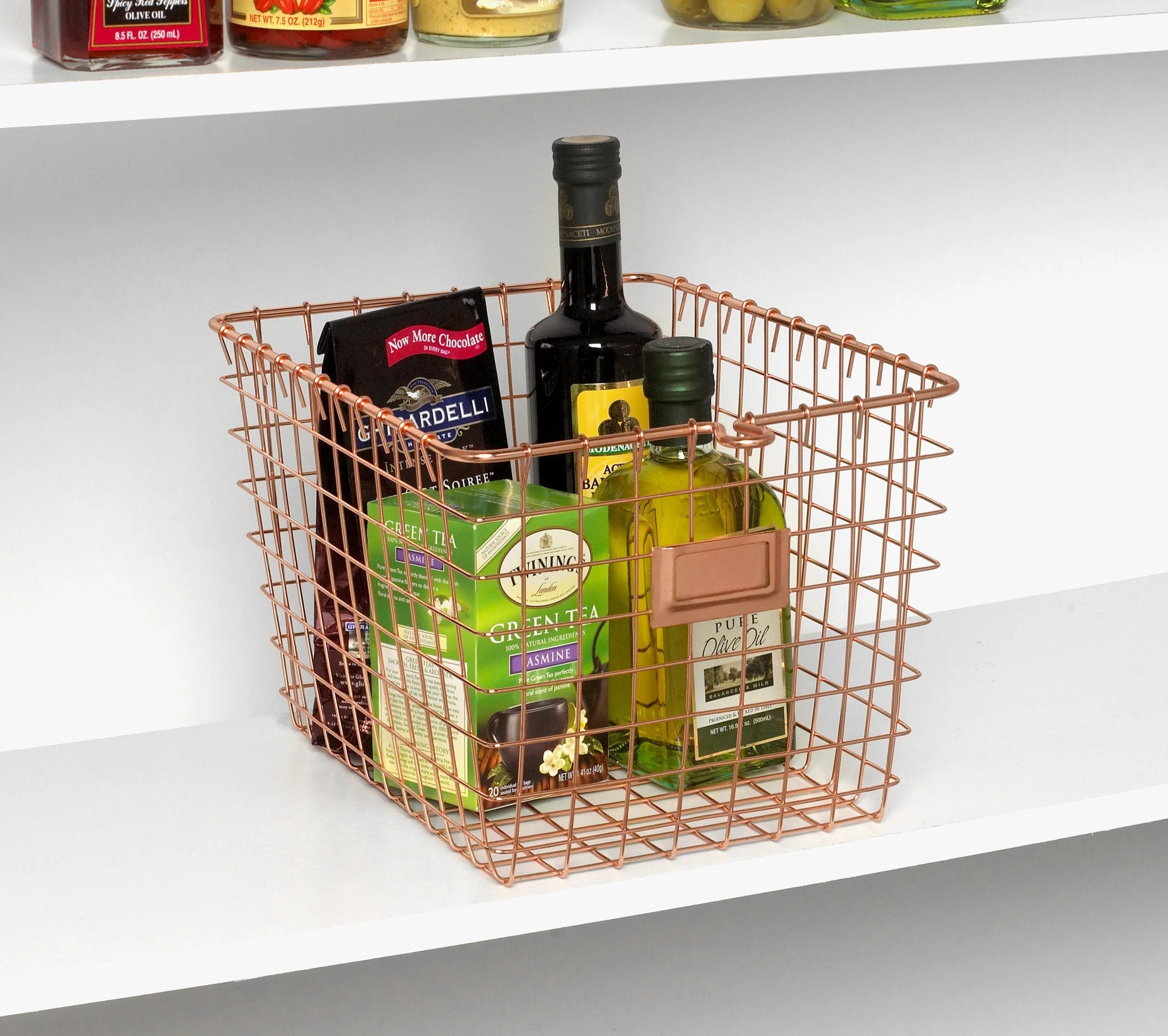 The basket in rose gold holding chocolate, tea, and olive oil