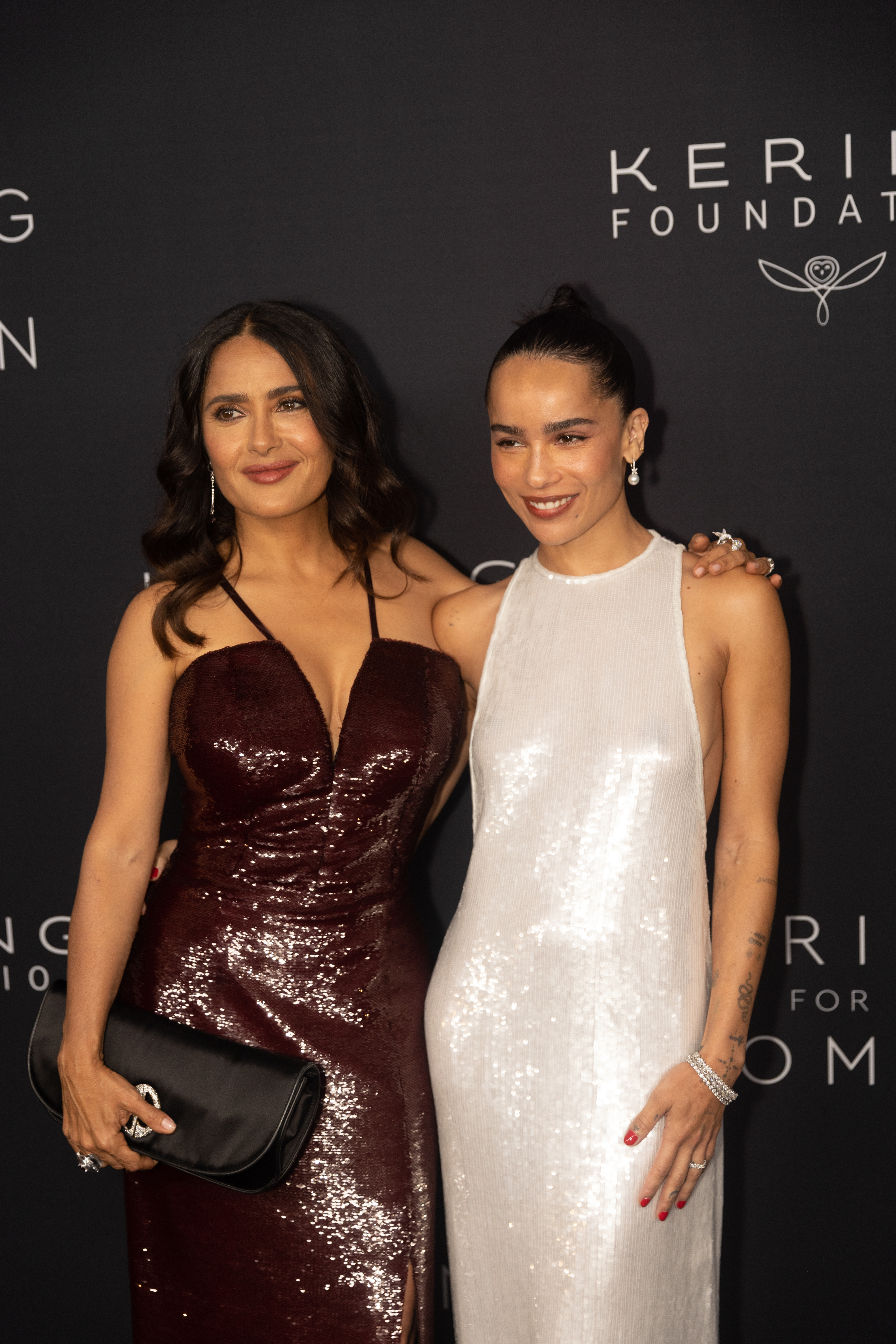 Salma Hayek and Zoë Kravitz at the event in shiny, sleeveless dresses