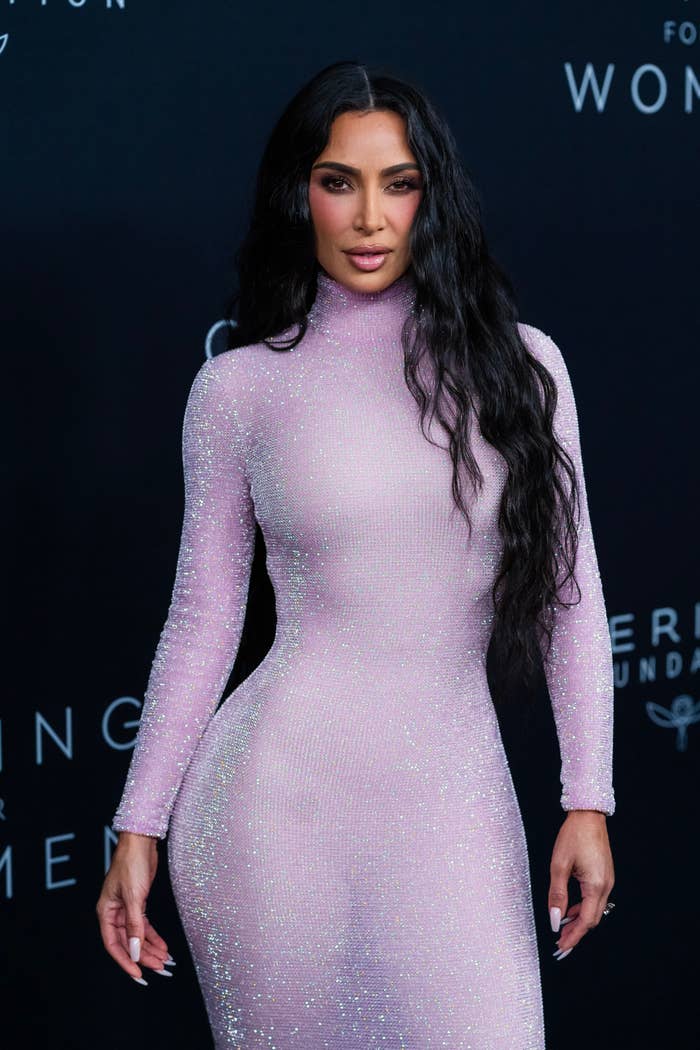 Close-up of Kim at a media event in a shiny turtleneck outfit