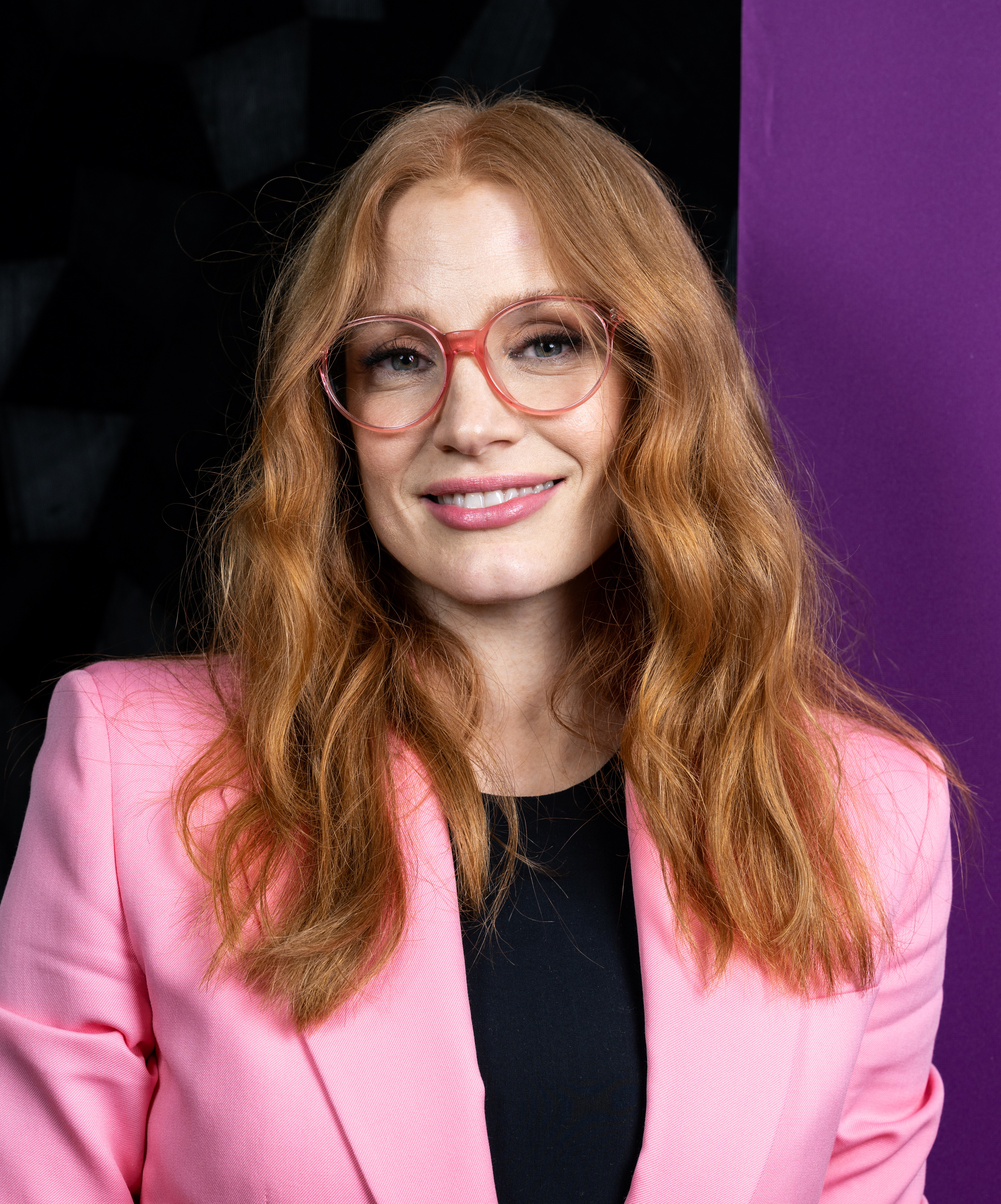 Close-up of Jessica smiling and wearing glasses and a suit jacket