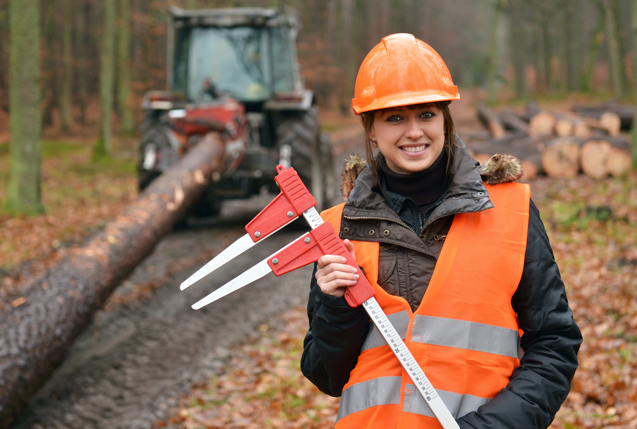 A woman wearing a hard hat and working in a forest
