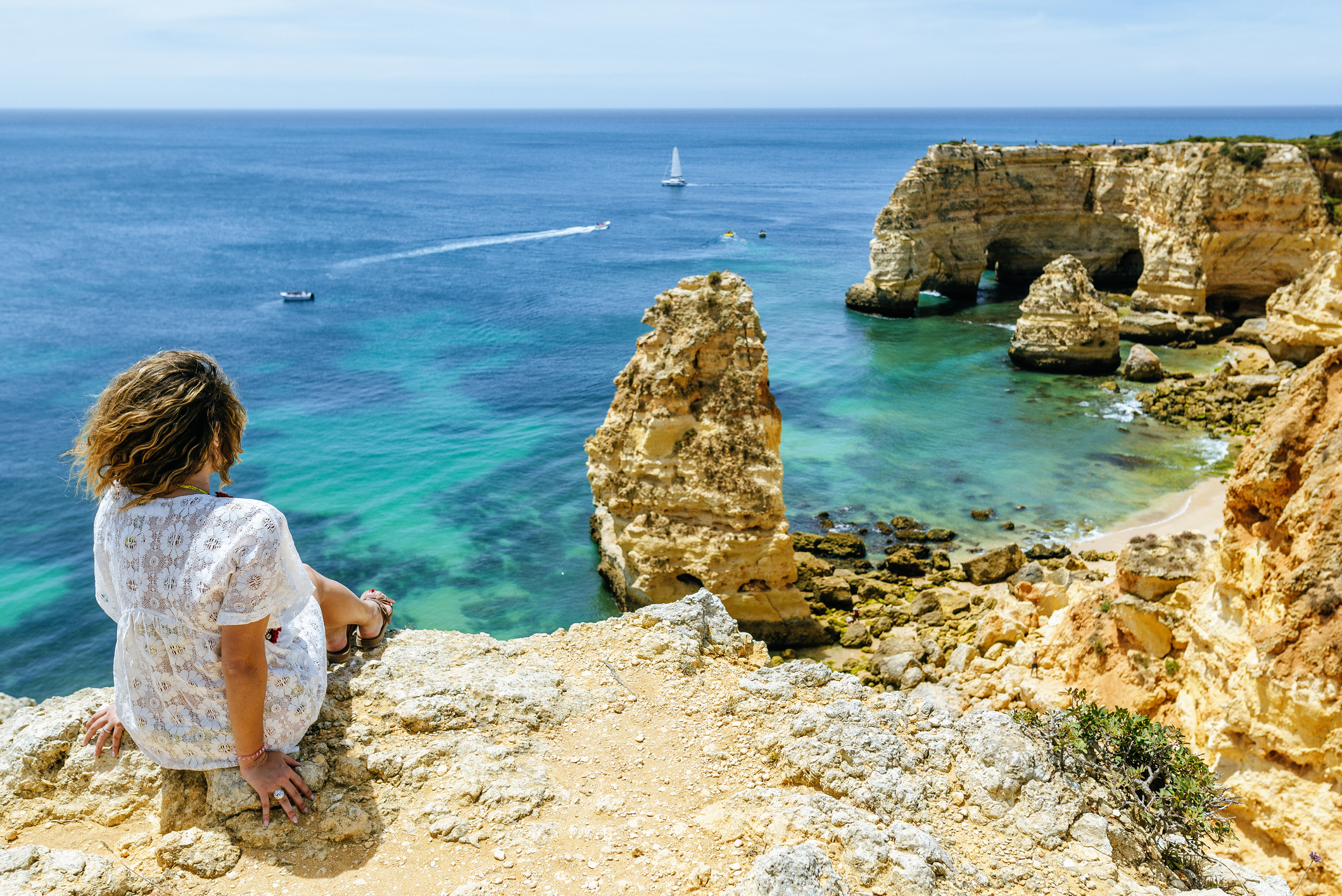 A woman sitting on a rock and looking at the scraggly coastline