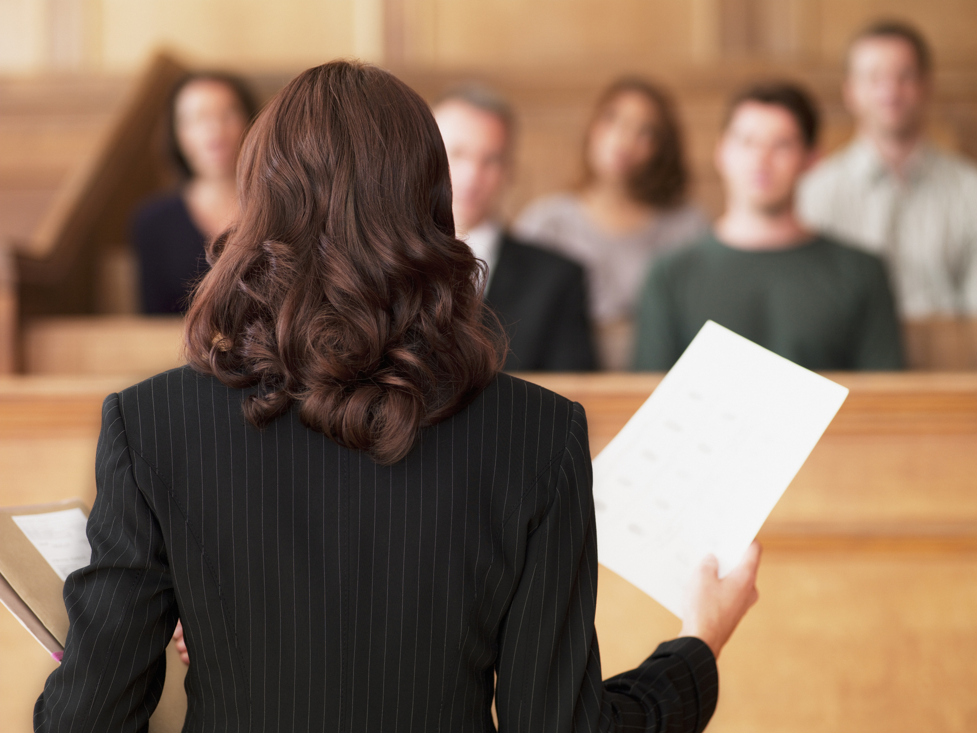 A woman standing before a jury in a courtroom