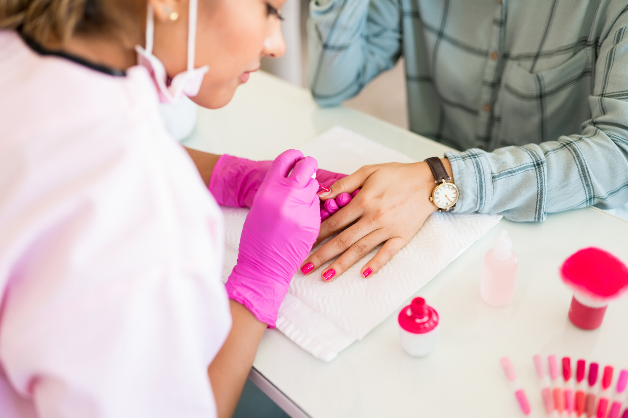 A woman wearing gloves and working on someone's nails