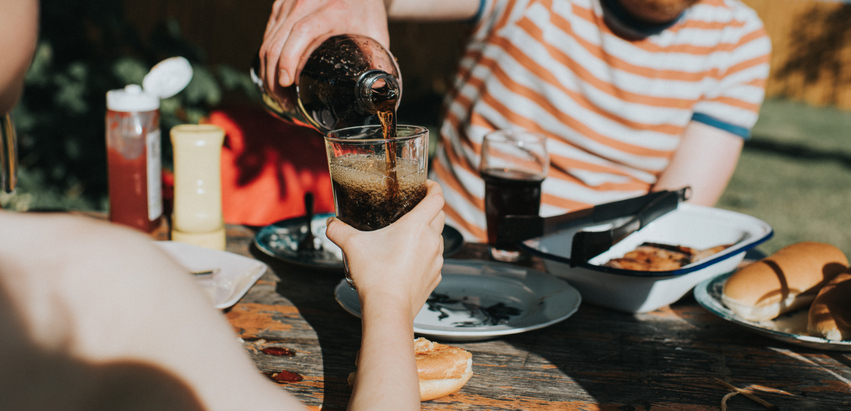 person pouring coke into a glass
