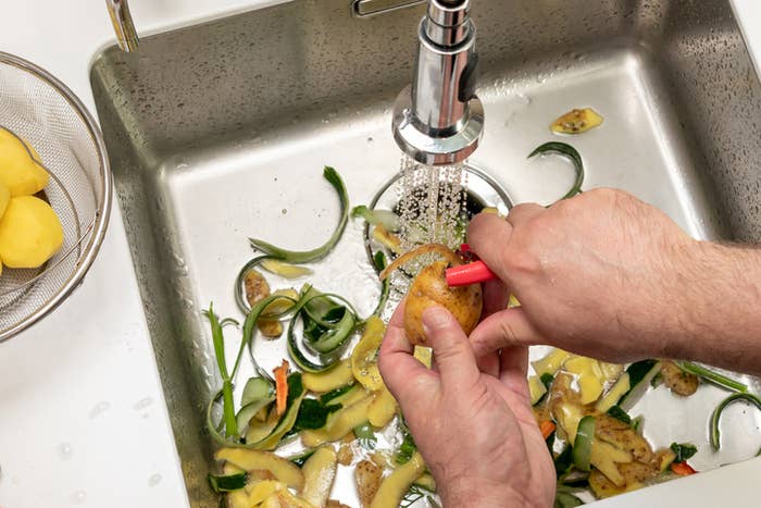 hand peeling potatoes in the sink