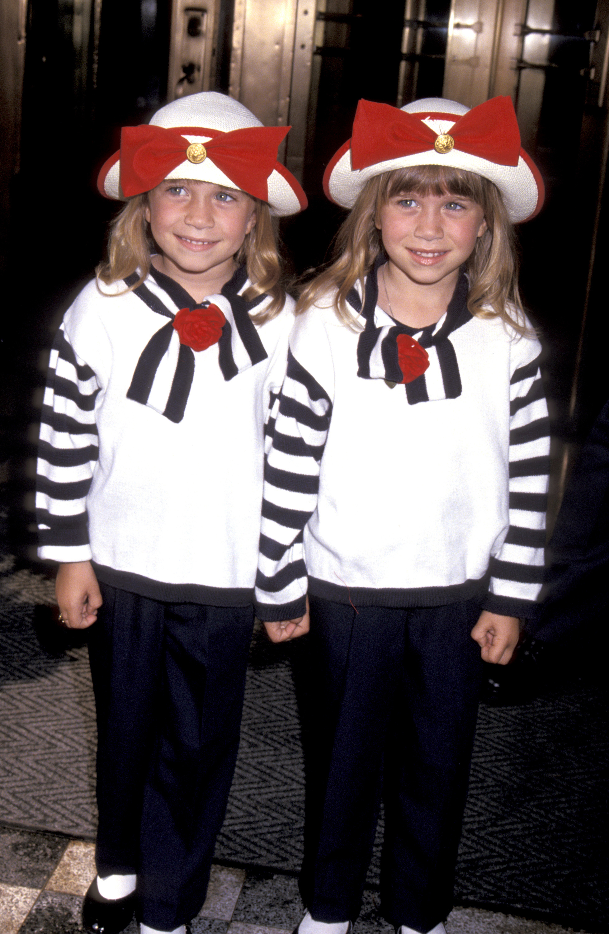 Mary-Kate and Ashley in matching sailor-type outfits and large hats with bows