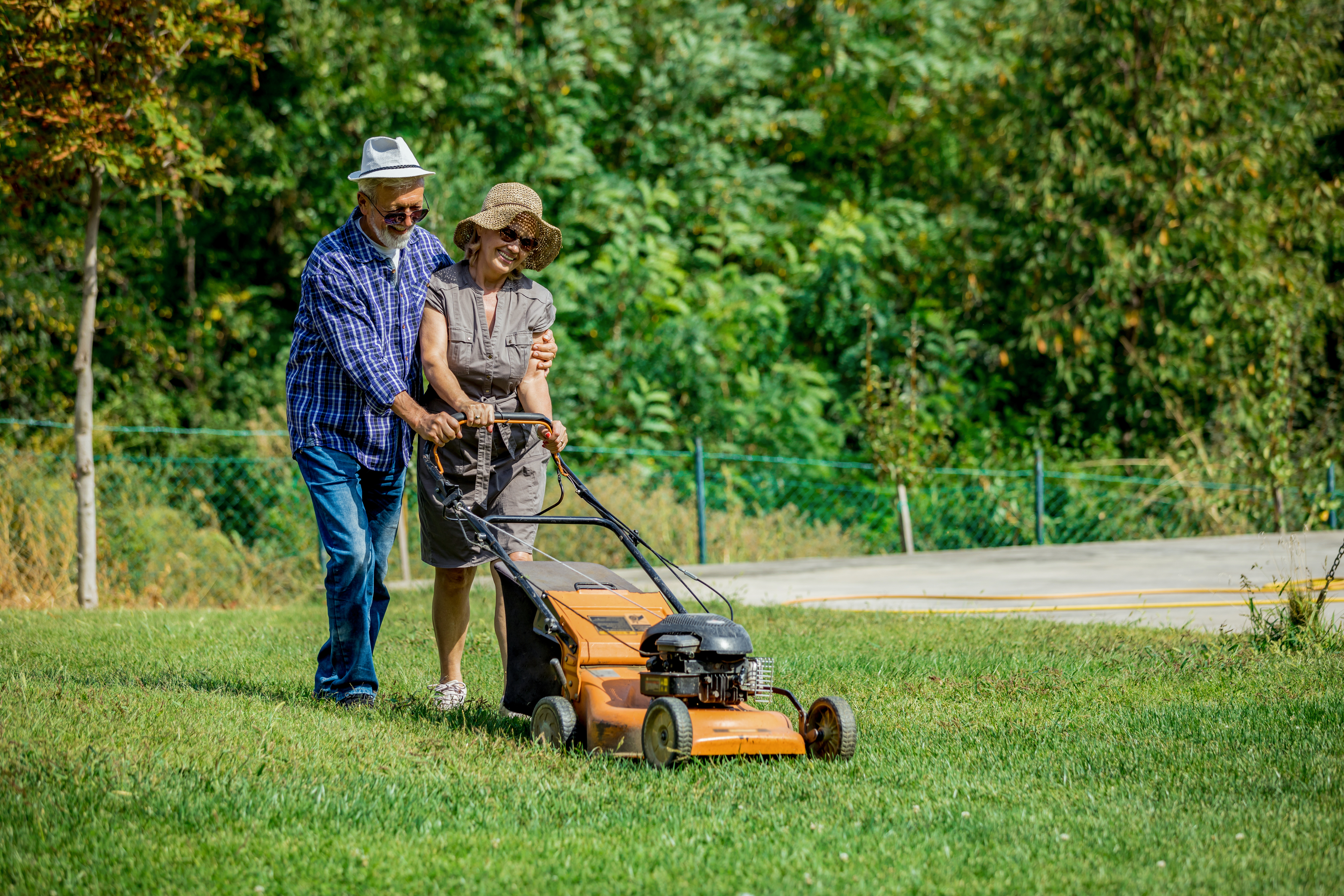 Two people mowing a lawn