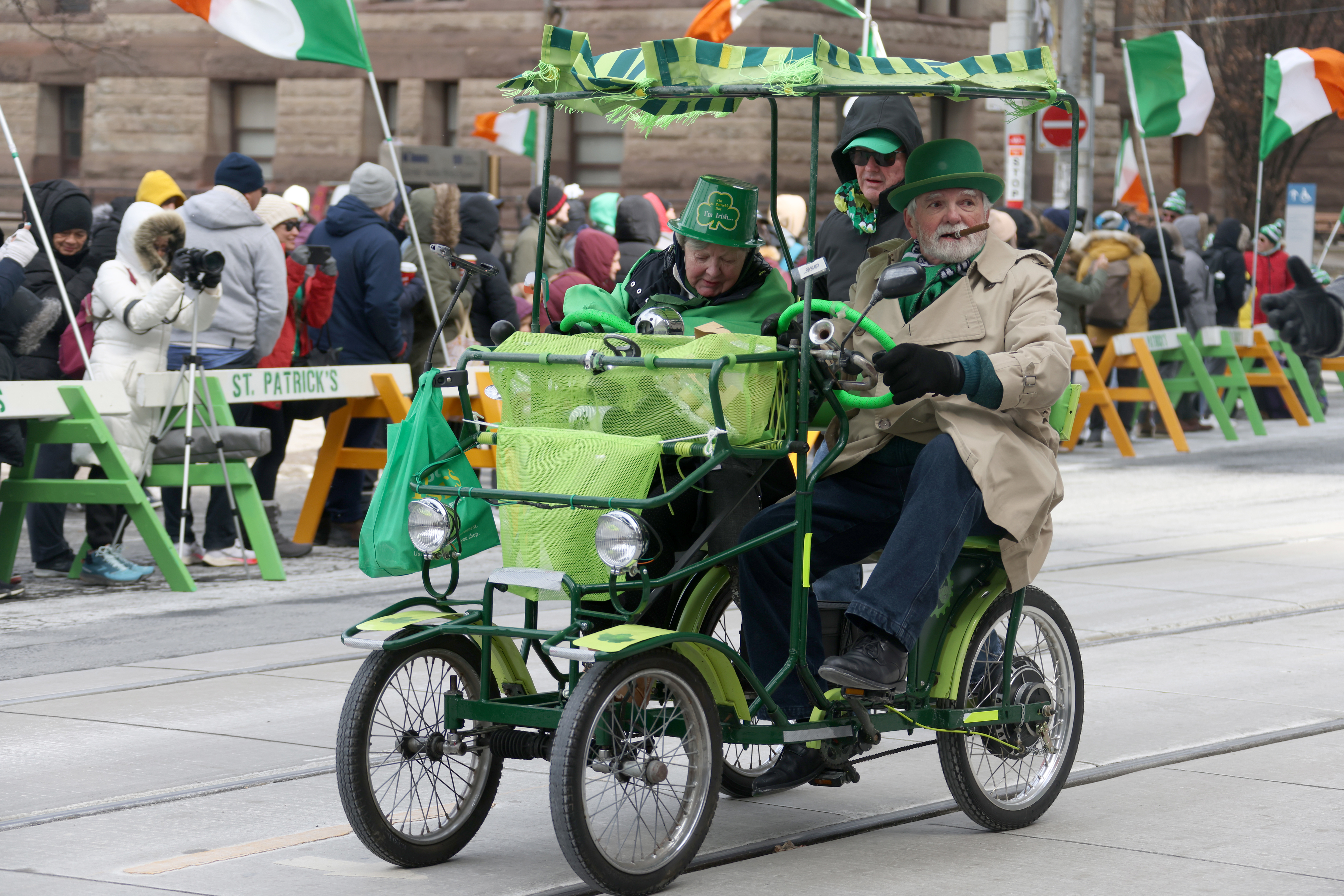 Three people in a green cart in a parade