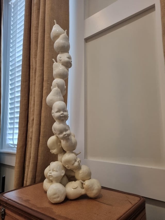 sculpture of baby heads in a tower that also look like pears