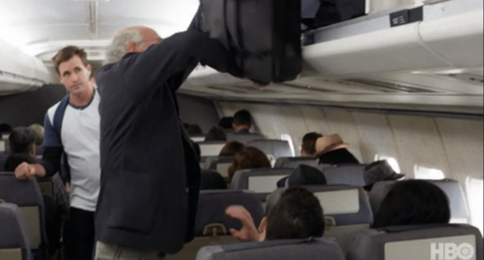 person putting luggage overhead in a plane