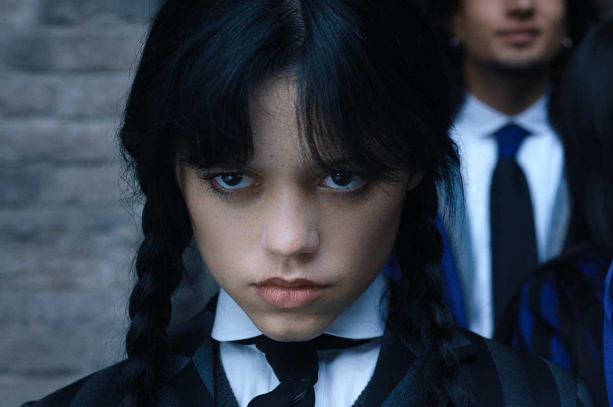 Wednesday Addams is staring intensely with braided hair and a somber school uniform