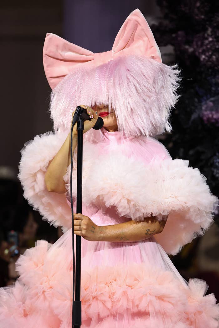 closeup of sia on stage with half her face covered in a large wig