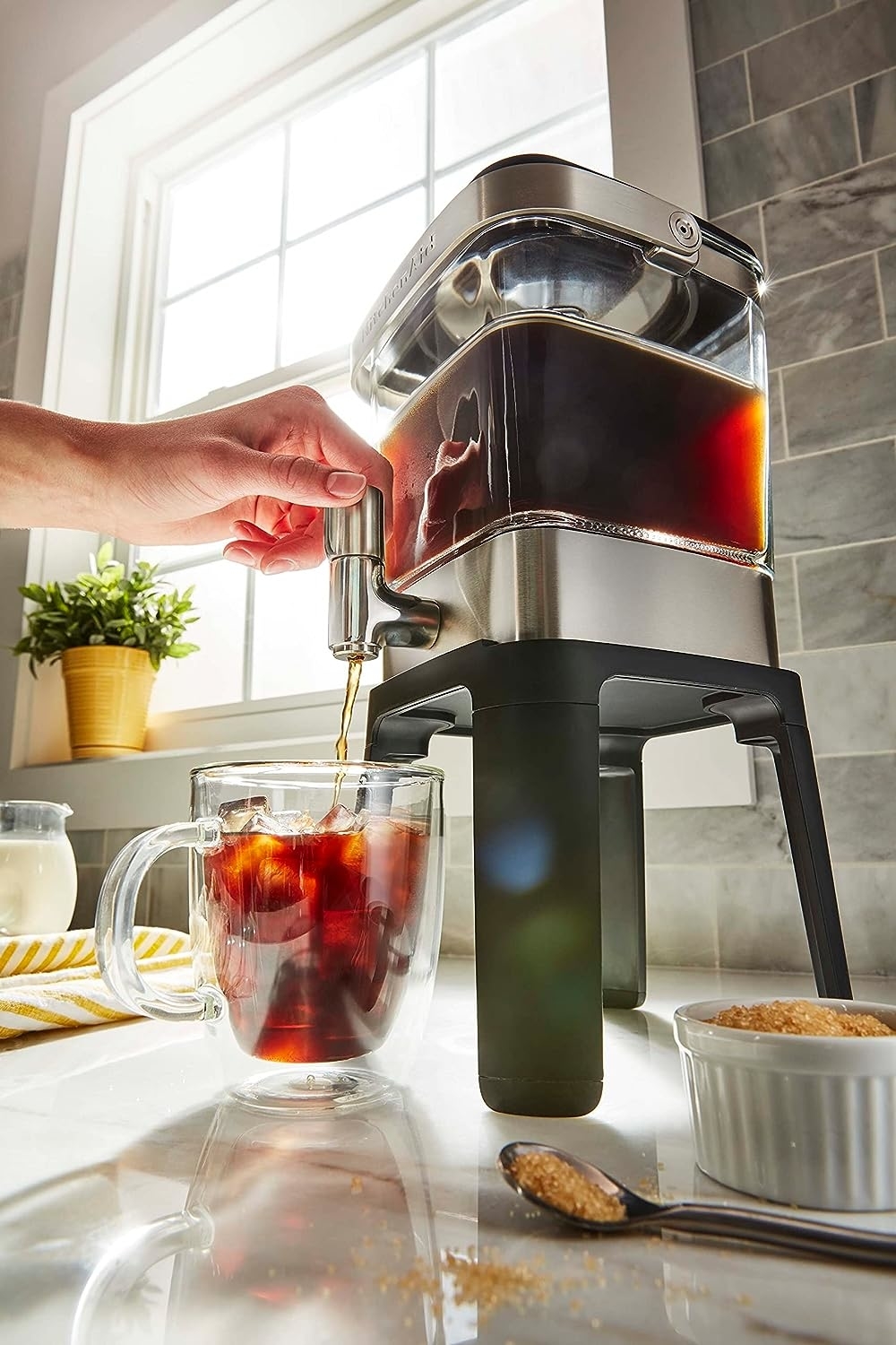 the cold brew maker with a hand using it to dispense coffee