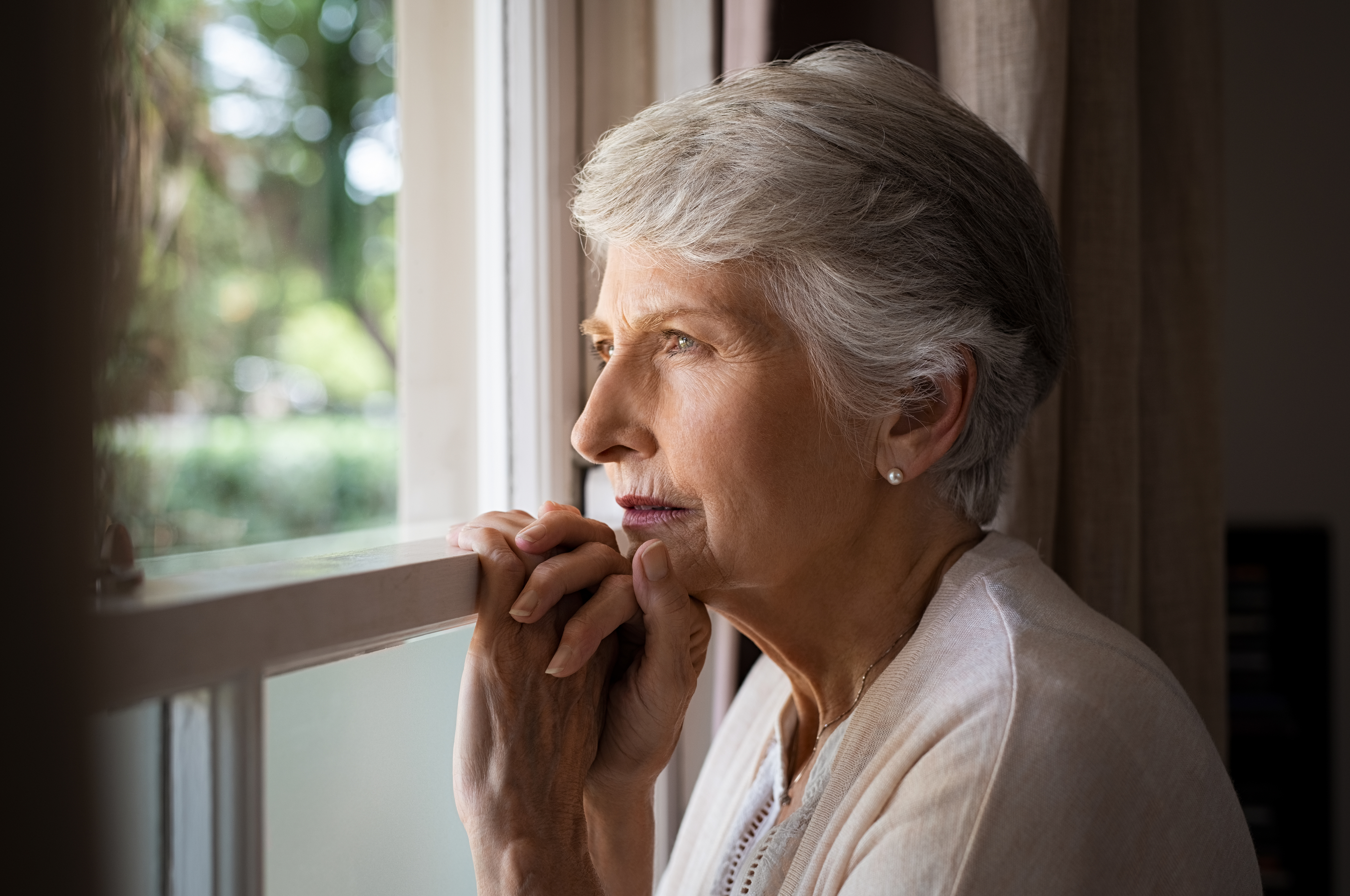 An older woman looking contemplatively out a window