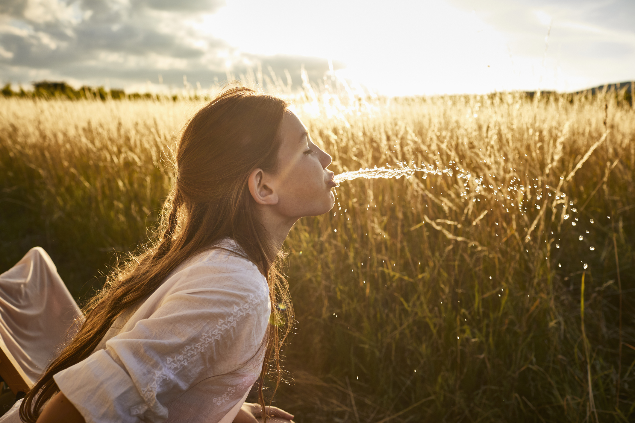 Kid spitting out water in a field