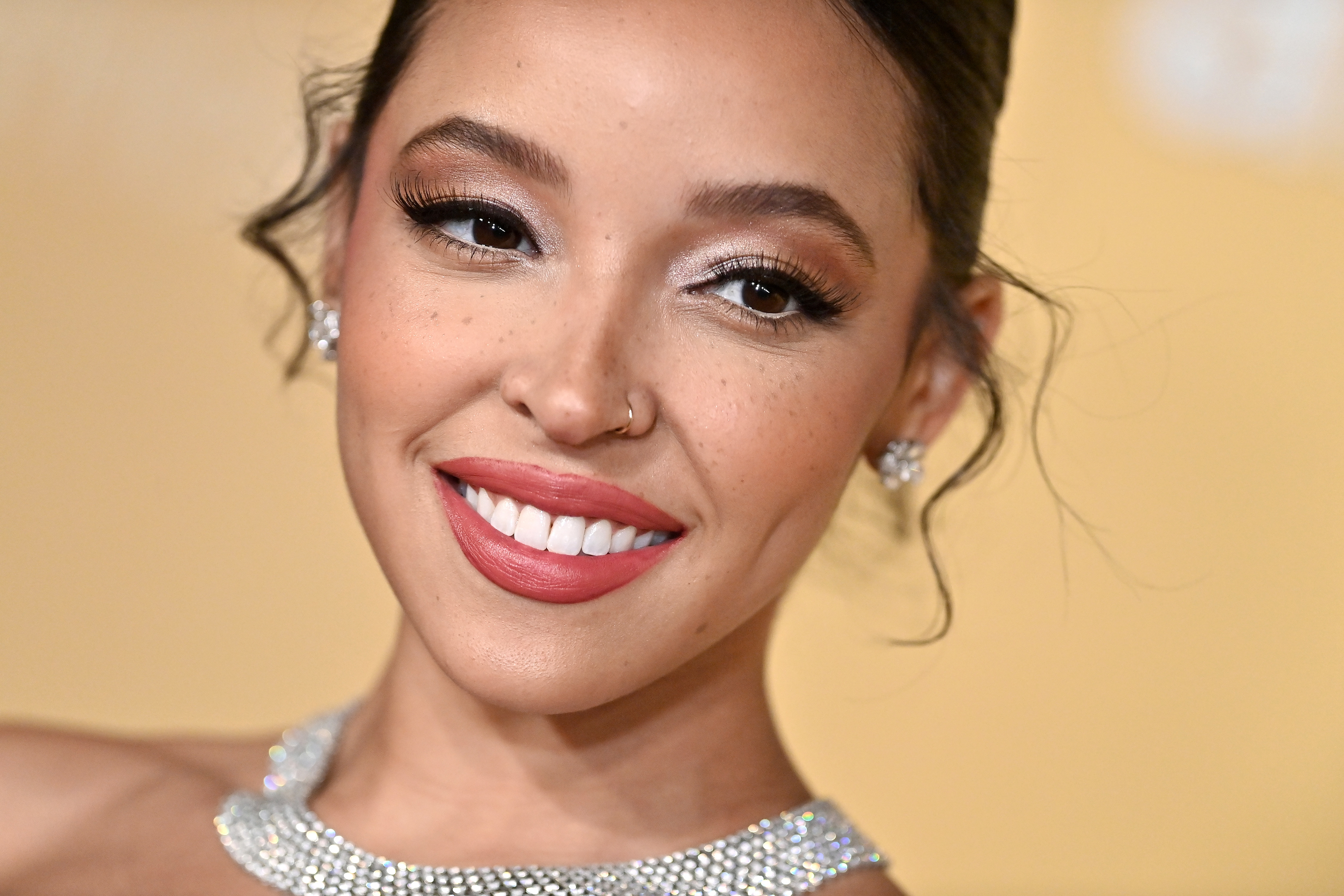Close-up of Tinashe at a media event smiling and wearing a bejeweled choker