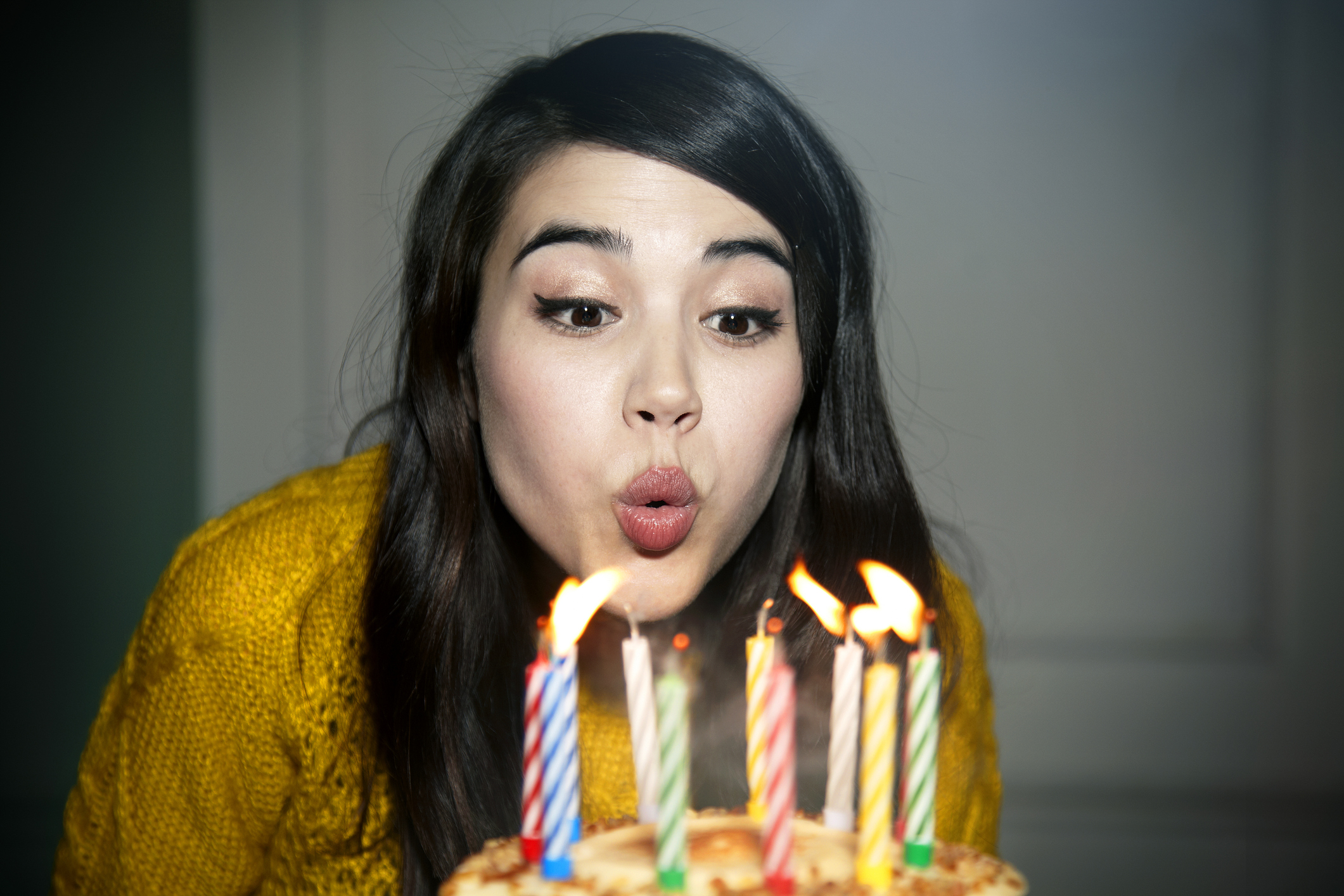 A person blowing out birthday candles on a cake