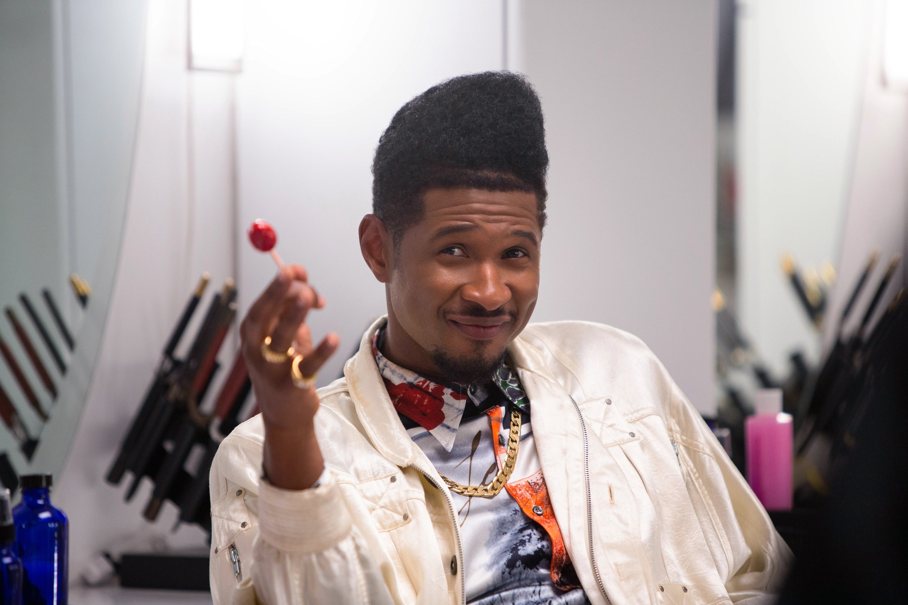Close-up of Usher smiling and holding a lollipop
