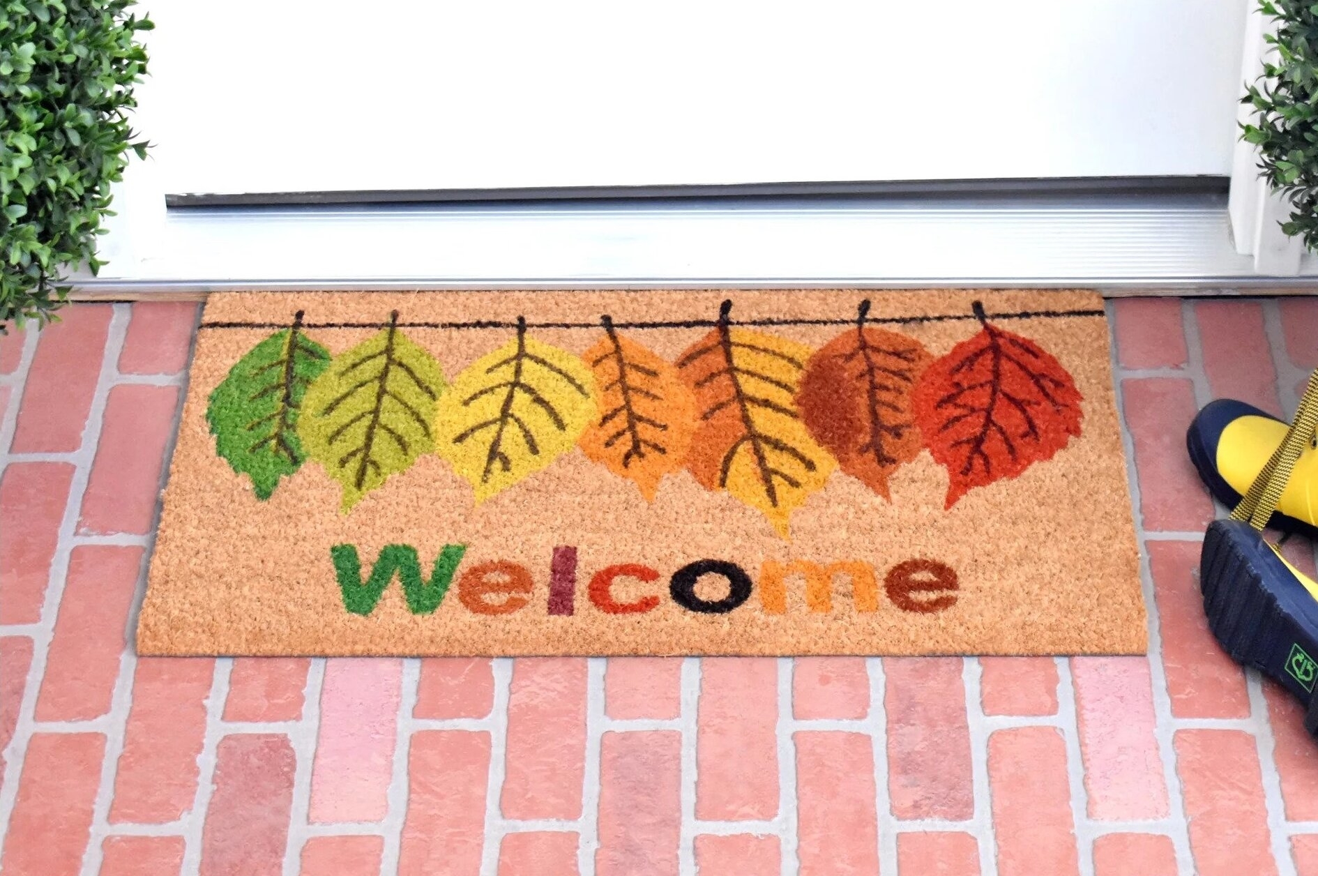 The doormat, which reads &quot;welcome&quot; and has leaves in various colors