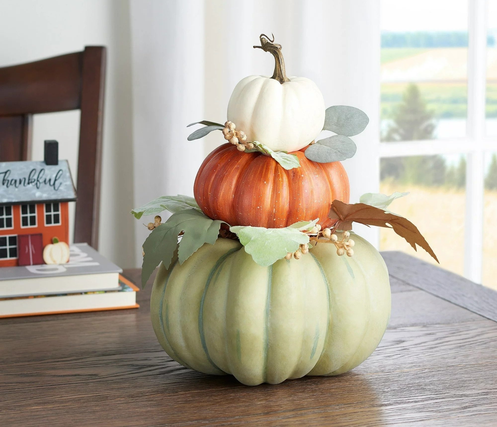 Three pumpkins stacked from smallest to largest in white, orange, and green respectively