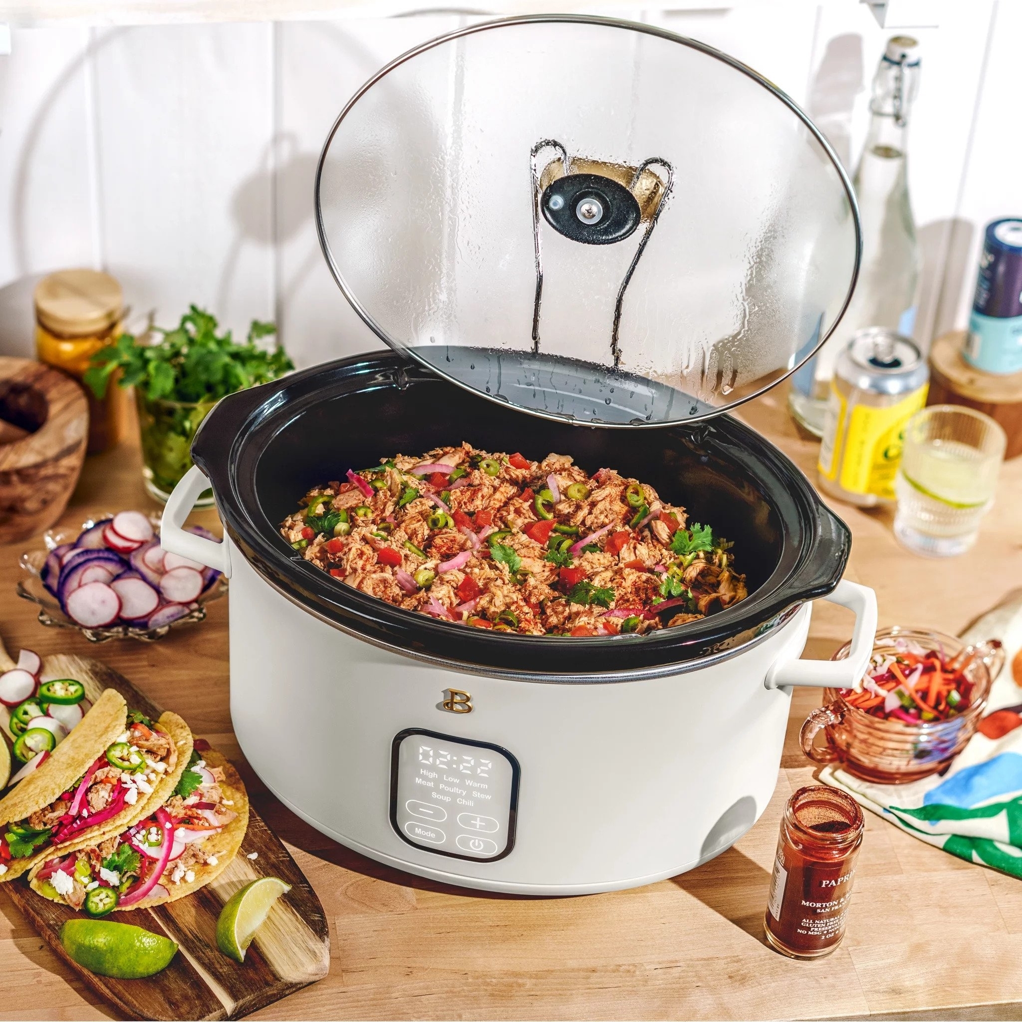 The white slow cooker with its lid open and supported by the rest